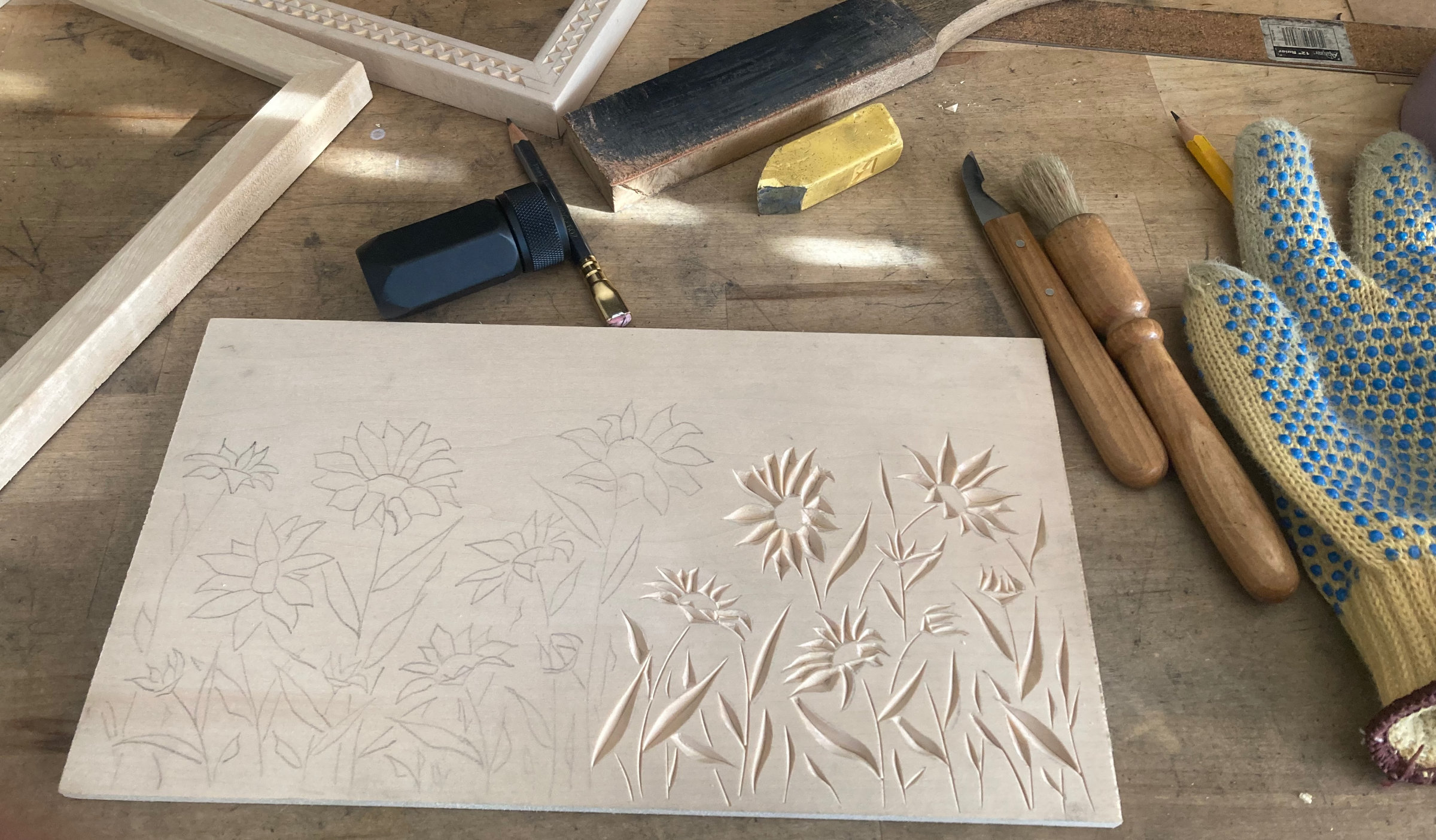 carving tools and a half-finished carving of sunflowers